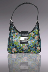 Floral patterned handbag with a black strap on a reflective surface