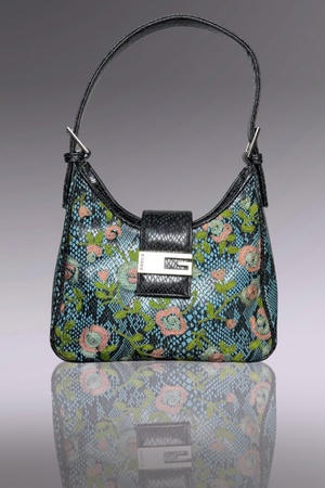 Floral patterned handbag with a black strap on a reflective surface