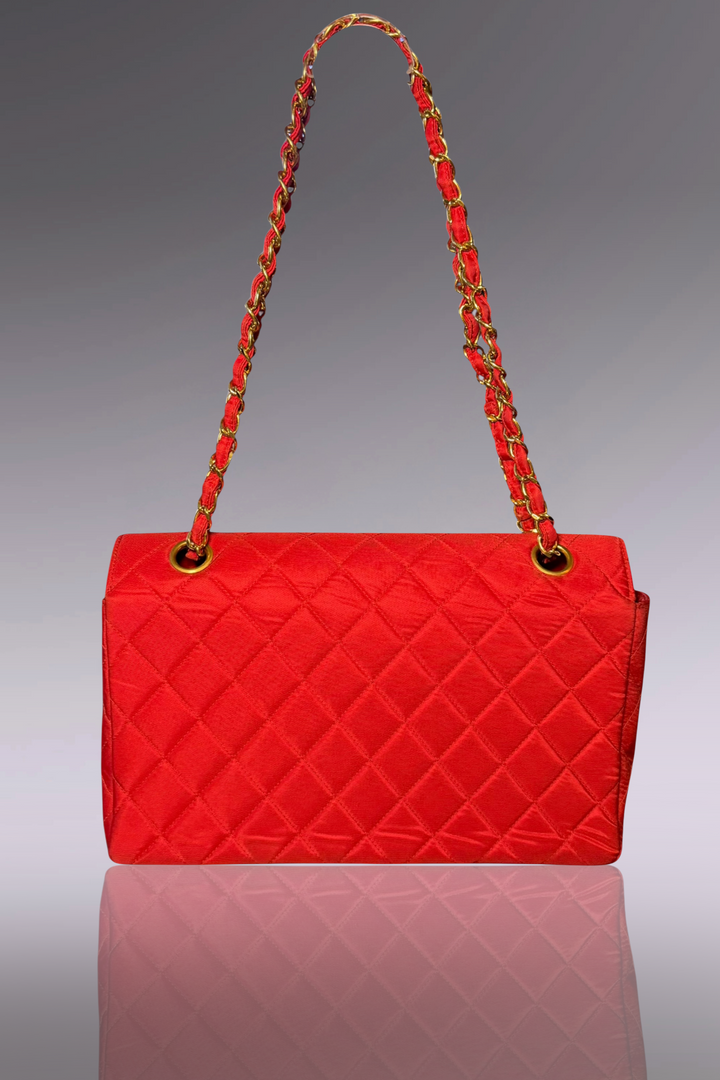 Red quilted handbag with a braided handle on a gray background