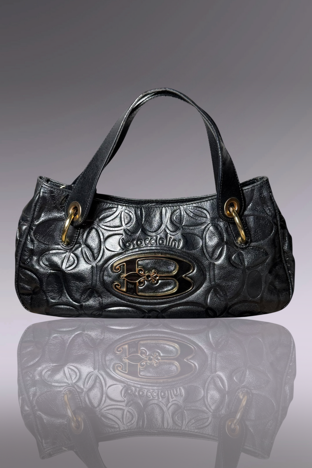 Black embossed handbag with gold accents on a gray background