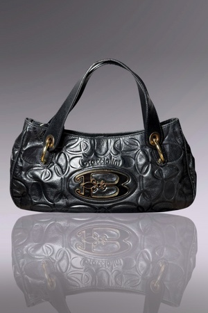Black embossed handbag with gold accents on a gray background