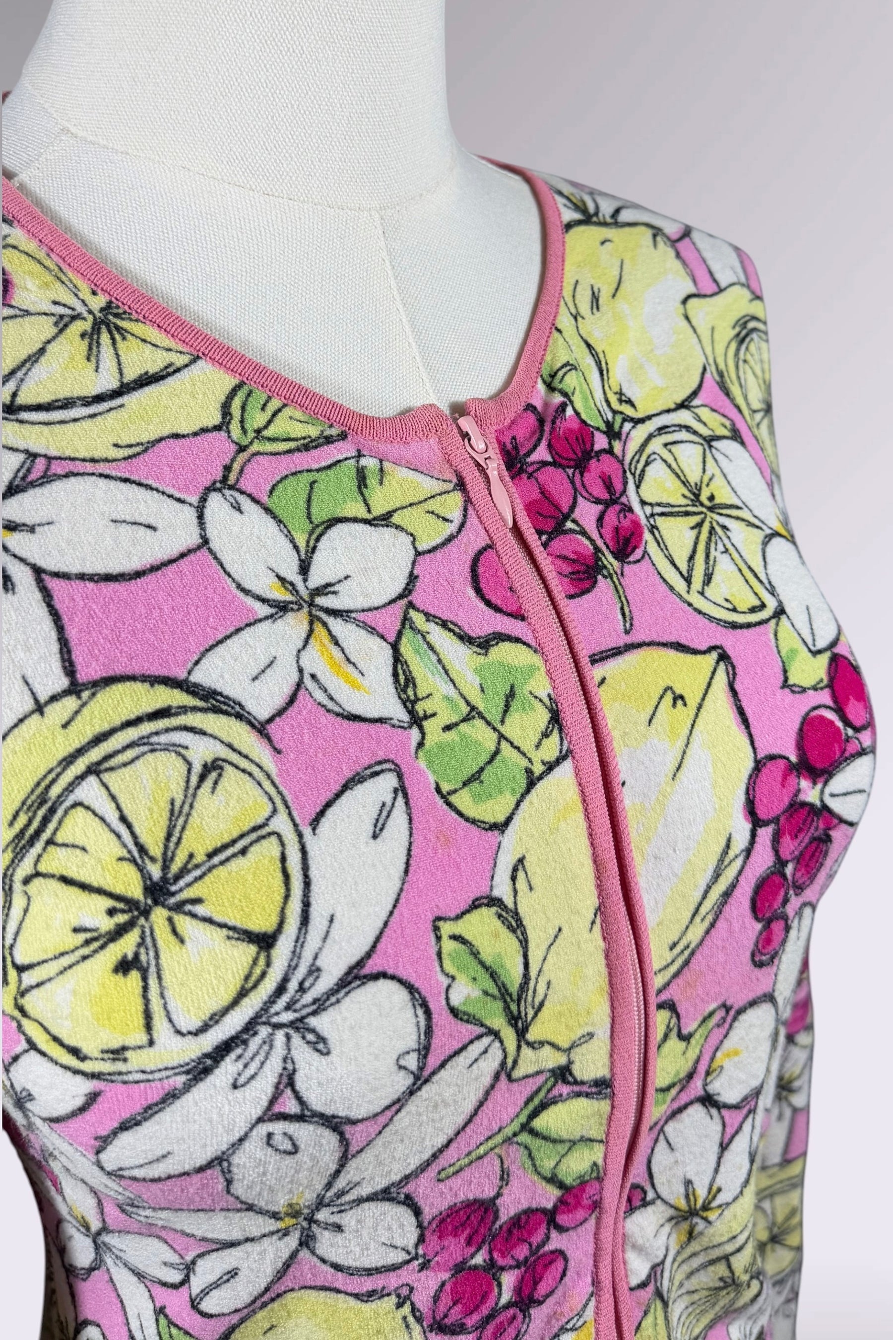 Mannequin wearing a top with a colorful lemon and flower pattern on a grey background