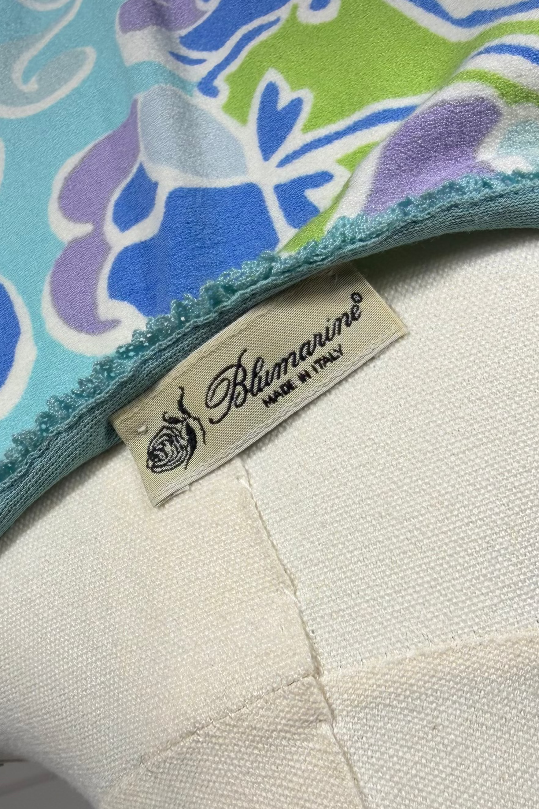 Close-up of a colorful fabric with a brand label on a white background