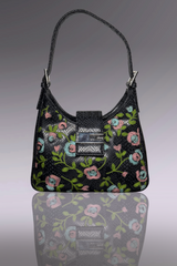 Black handbag with floral embroidery on a reflective surface