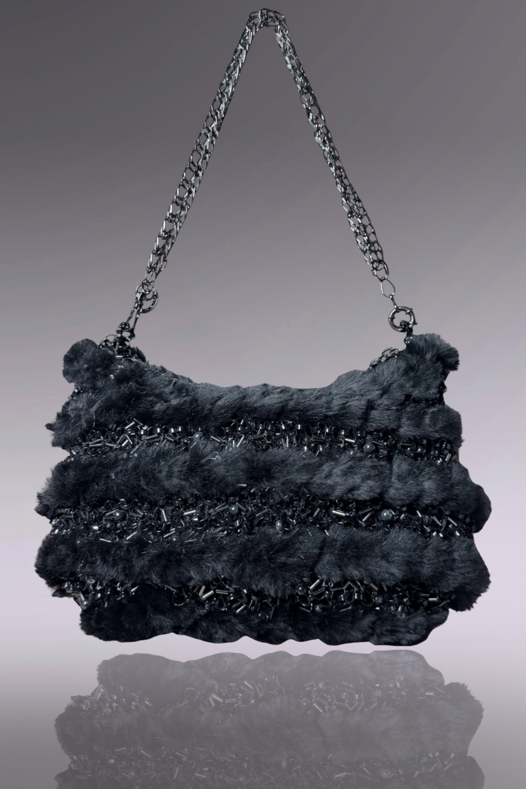 Black textured handbag with chain handle on a reflective surface