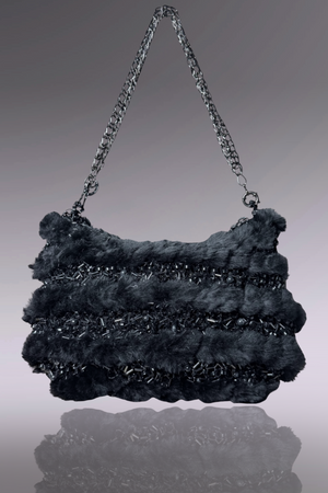 Black textured handbag with chain handle on a reflective surface