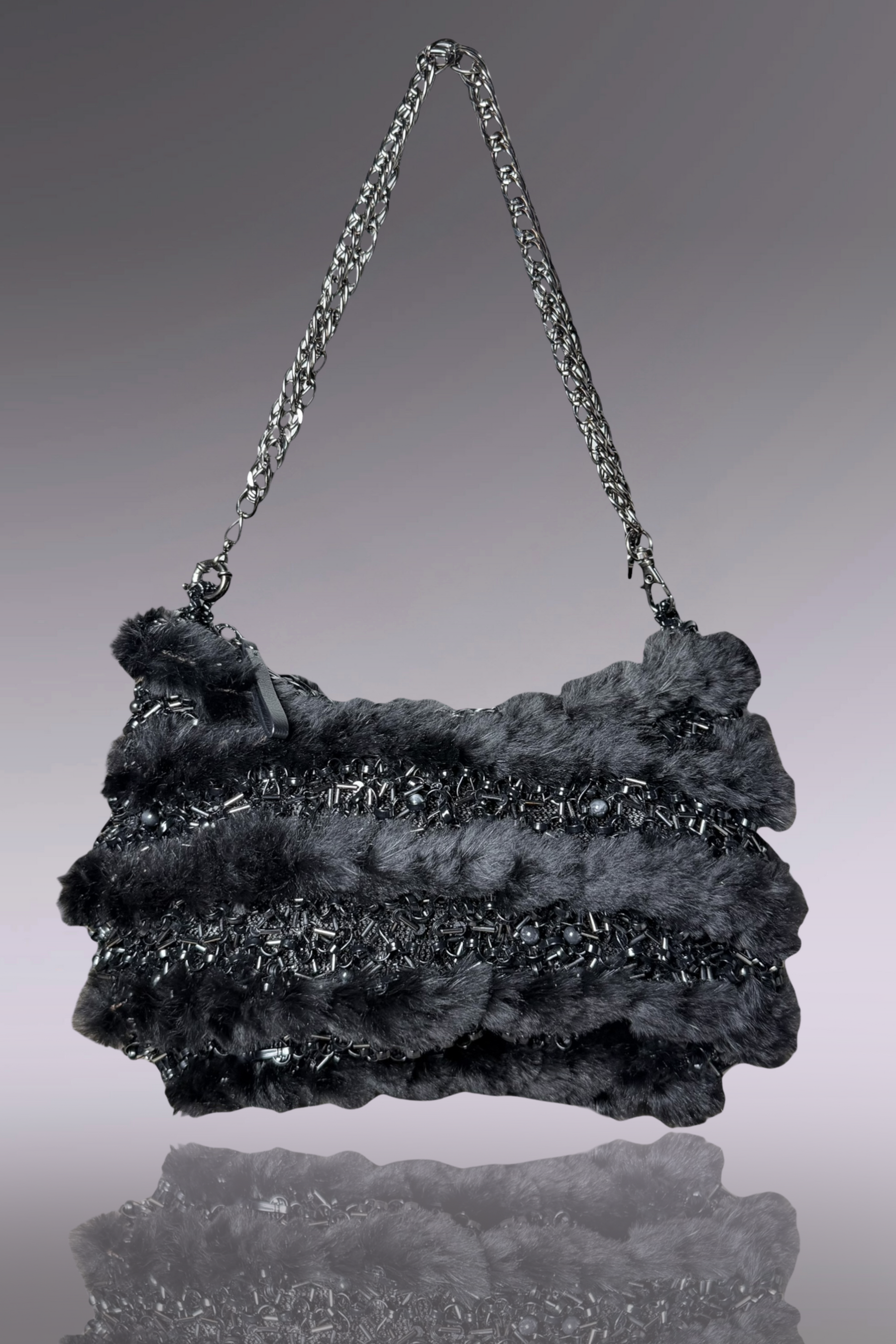 Textured handbag with chain strap on a reflective surface