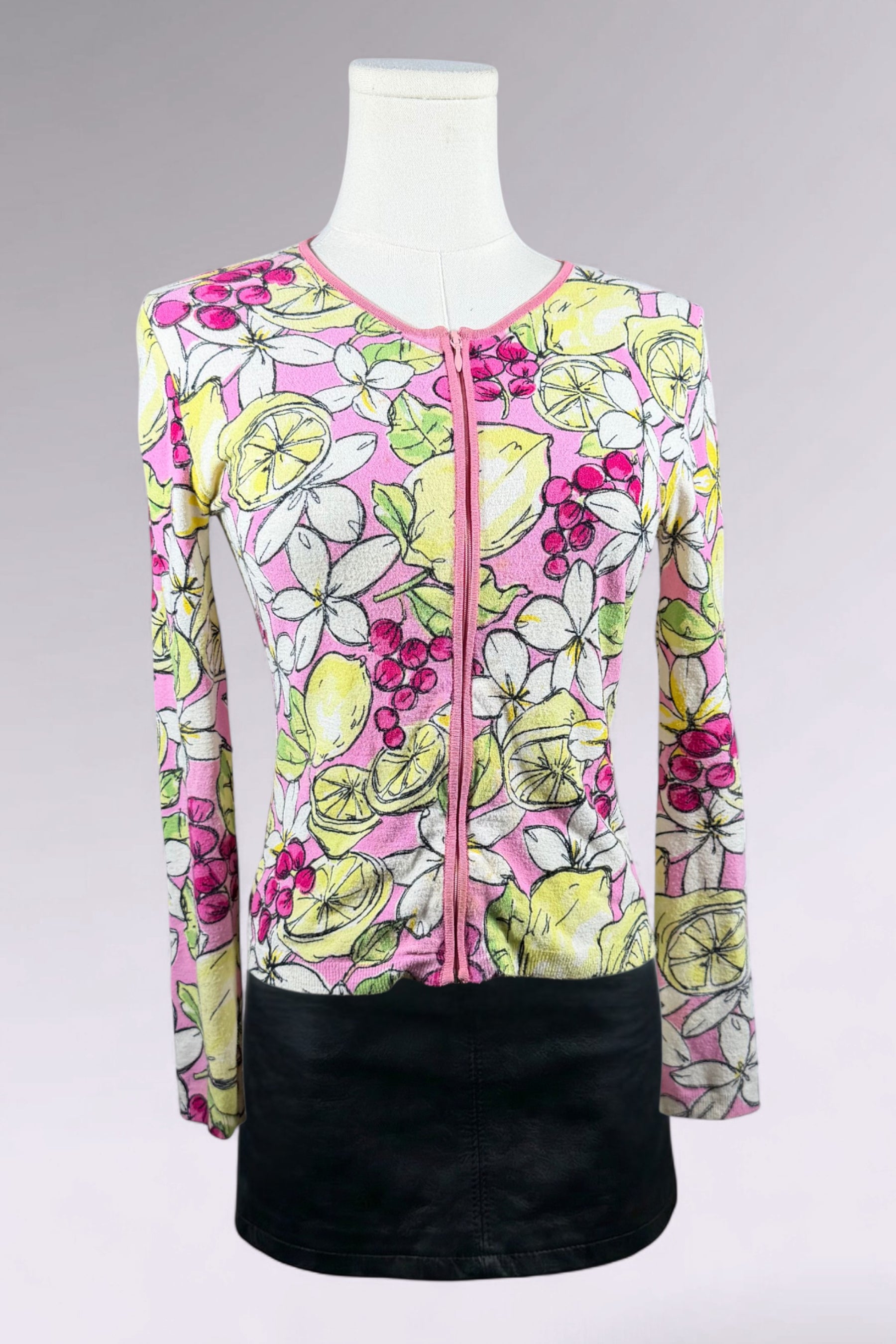 Colorful floral and fruit patterned top on a mannequin against a gray background
