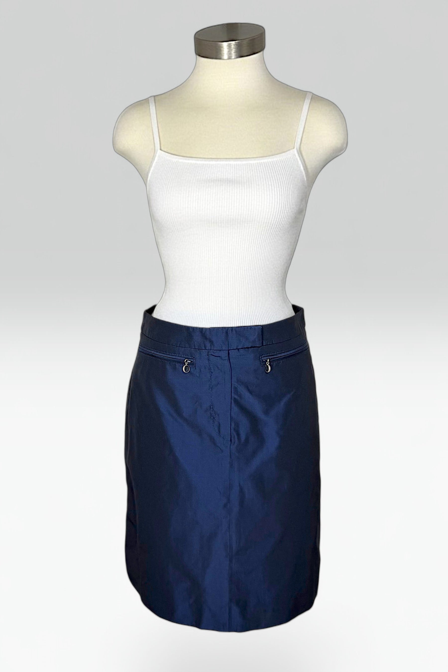 A navy blue mini skirt displayed on a mannequin torso, styled with a white ribbed camisole top against a light gray studio background.